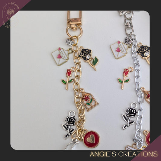 A handmade bookish charm with a silver-toned chain featuring cozy reading-themed enamel charms, including roses, hearts, a coffee cup charm, and an “I Love Books” tag at the end. Styled next to a book for a warm, inviting bookish aesthetic, this charm is designed for readers who love coffee, cozy reading moments, and thoughtful Valentine’s or Galentine’s Day gifts.