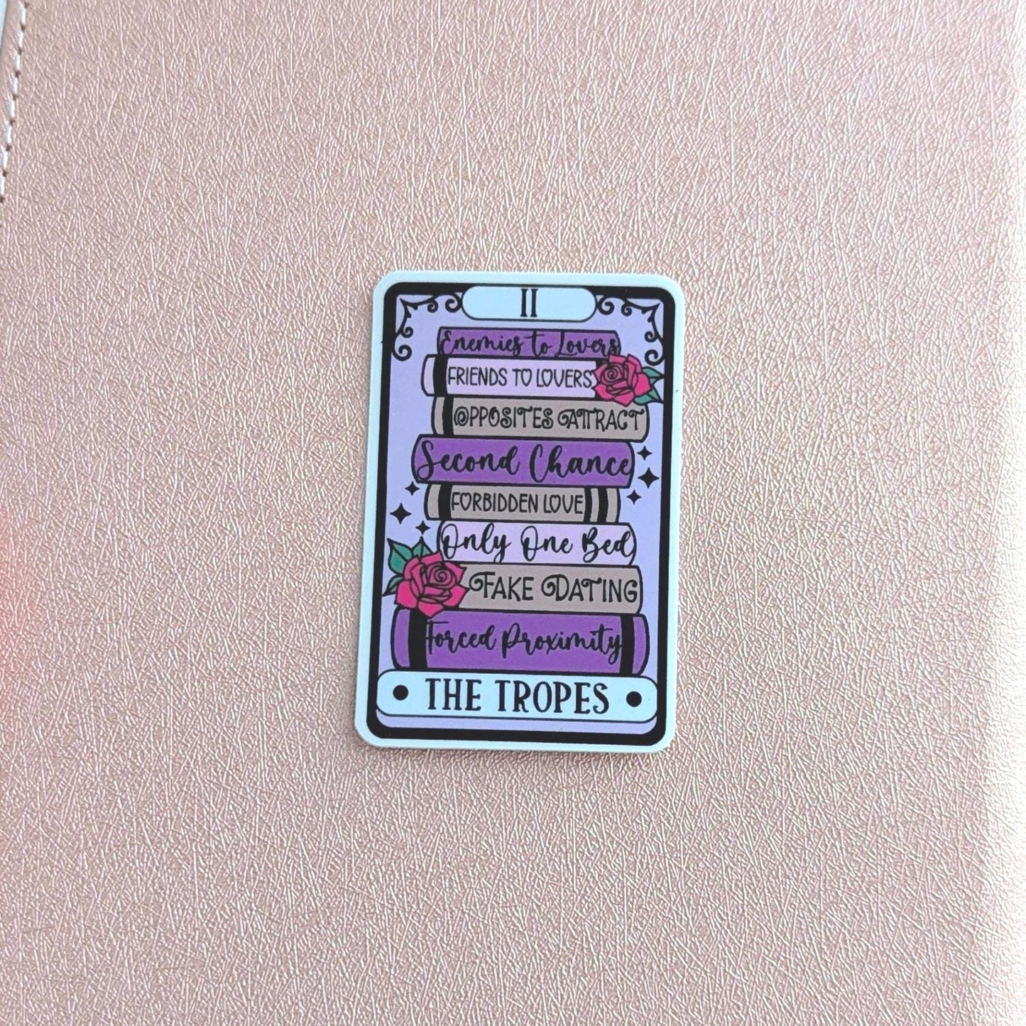 Pink notebook with a colorful card featuring text and graphics on a blurred background