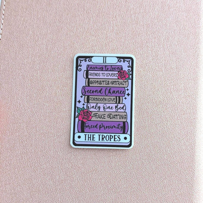 Pink notebook with a colorful card featuring text and graphics on a blurred background