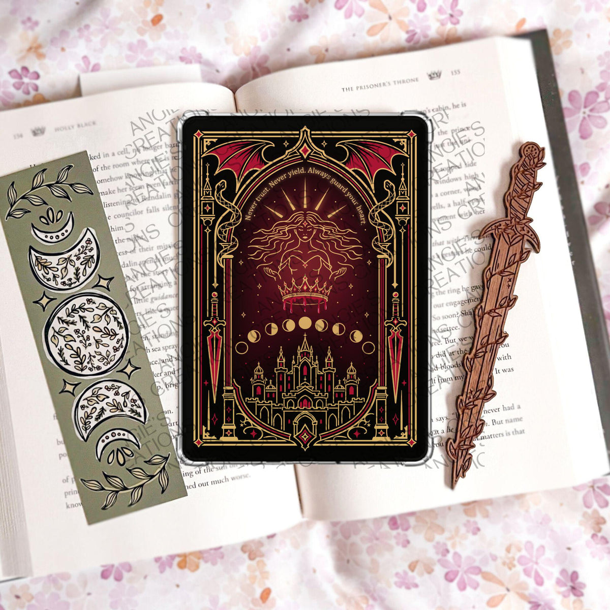 May include: A rectangular tablet case featuring a dark red and black illustration of a figure with a crown, a castle, and the text 'Never trust. Never yield. Always guard your heart.' Flanked by a green moon phase bookmark and a wooden sword bookmark.