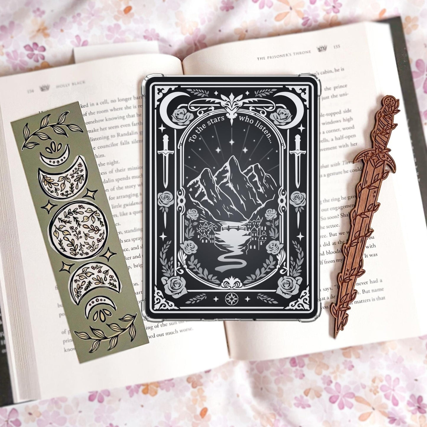 Black and silver tarot-card-style Kindle insert with mountains, a river, daggers, roses, moons, and the text "To the stars who listen."