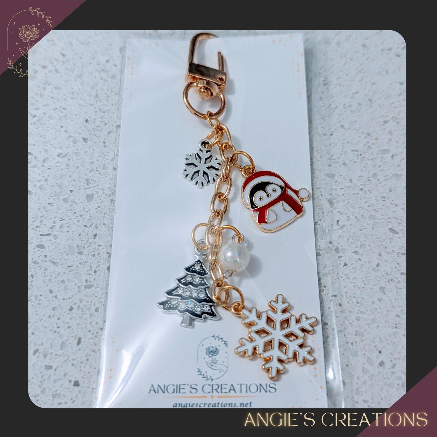 A festive winter charm chain featuring a penguin in a red scarf, snowflake charms, a Christmas tree charm, a bow charm, and a pearl bead, attached to gold or silver hardware. Handmade seasonal accessory perfect for decorating Kindles, bags, planners, or keys.