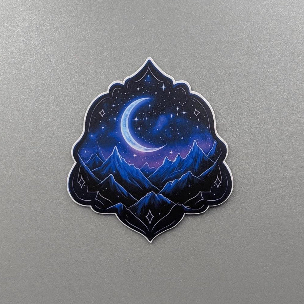 Angie's Creations waterproof sticker featuring a deep blue night sky scene with a glowing crescent moon, star-filled galaxy, and dark mountain silhouettes inside an ornate gothic arch shape. Romantasy and dark fantasy inspired waterproof die-cut sticker designed in Ottawa Canada, perfect for Kindle cases, laptops, water bottles, and journals.