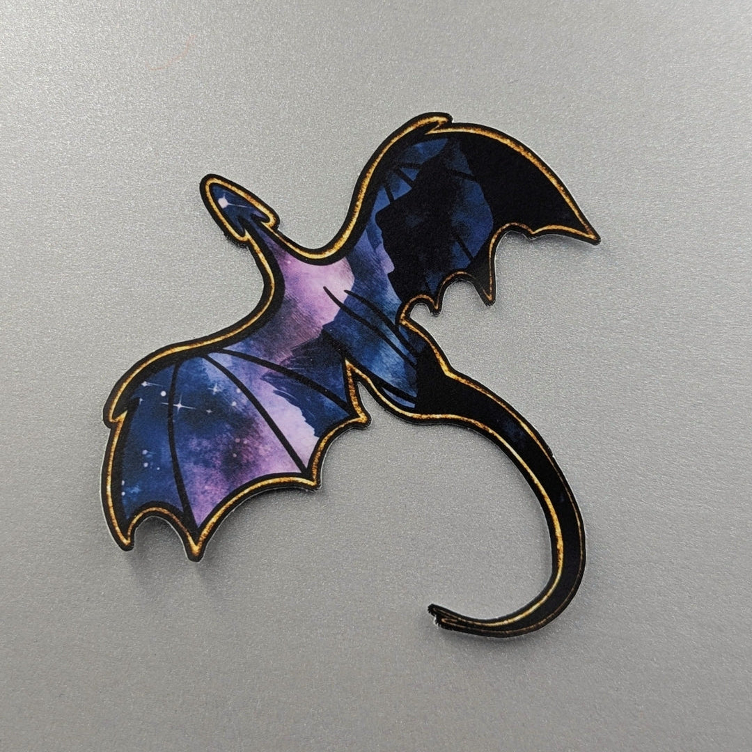 Angie's Creations waterproof die-cut sticker featuring a soaring dragon with deep blue and purple galaxy-filled wings and a gold outlined silhouette, stars glittering through the wing membranes. Fourth Wing and ACOTAR inspired waterproof sticker designed in Ottawa Canada, perfect for Kindle cases, laptops, water bottles, and journals.