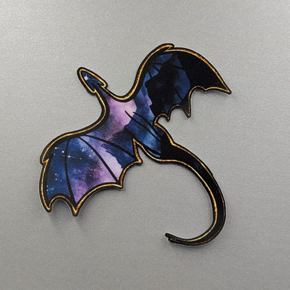 Angie's Creations waterproof die-cut sticker featuring a soaring dragon with deep blue and purple galaxy-filled wings and a gold outlined silhouette, stars glittering through the wing membranes. Fourth Wing and ACOTAR inspired waterproof sticker designed in Ottawa Canada, perfect for Kindle cases, laptops, water bottles, and journals.