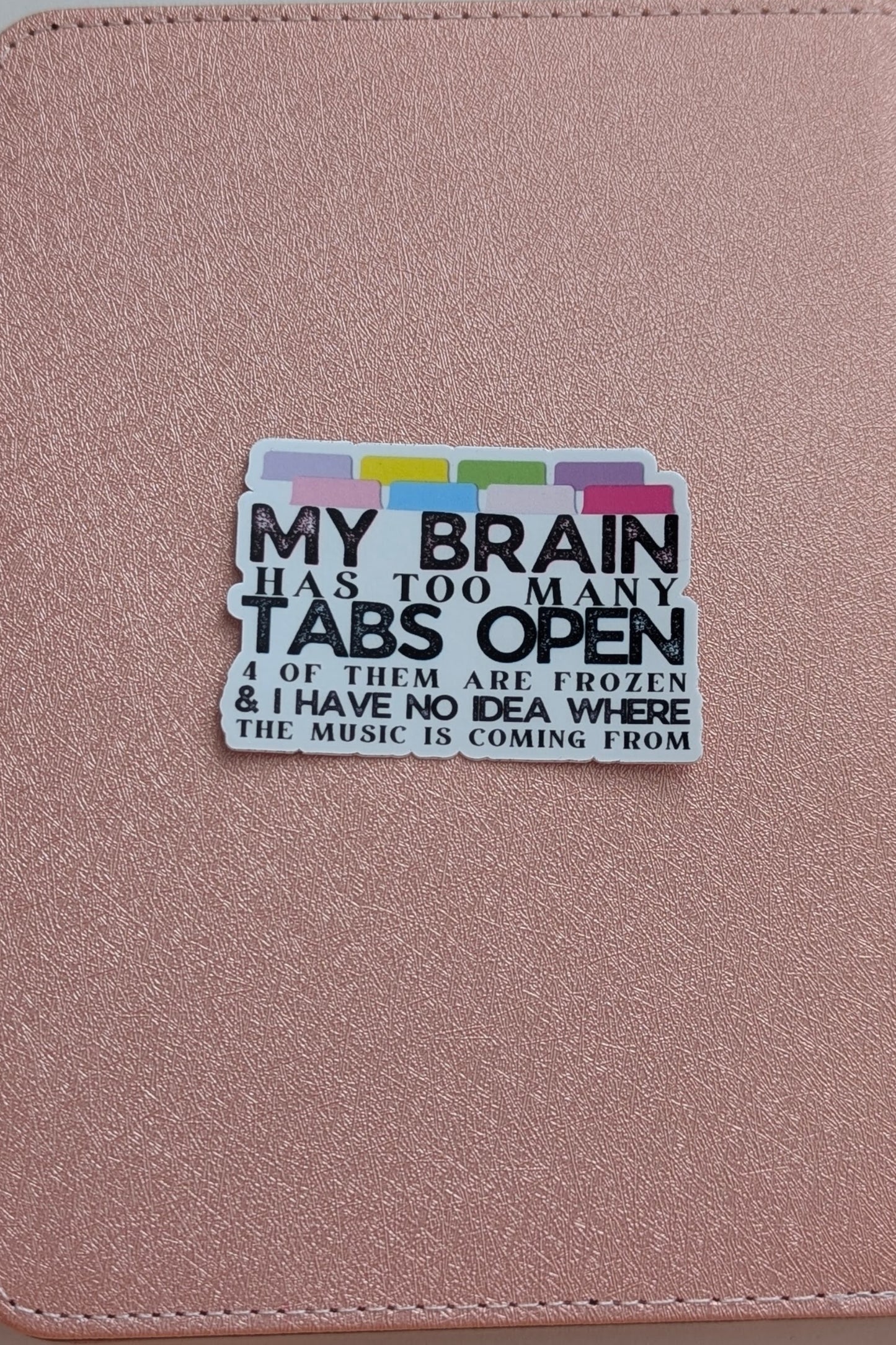Pink notebook with a humorous sticker about open tabs on a pink background