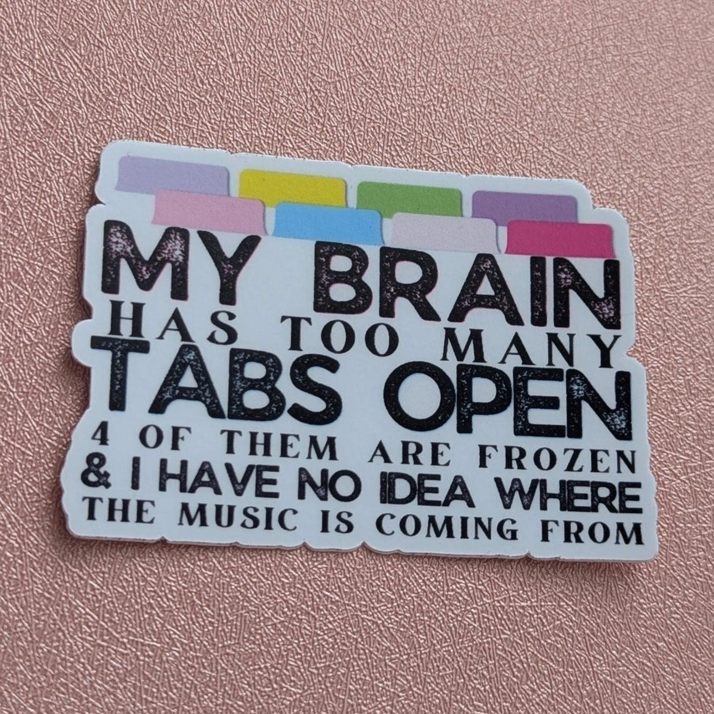 Sticker with text 'My brain has too many tabs open 4 of them are frozen & I have no idea where the music is coming from' on a pink background.