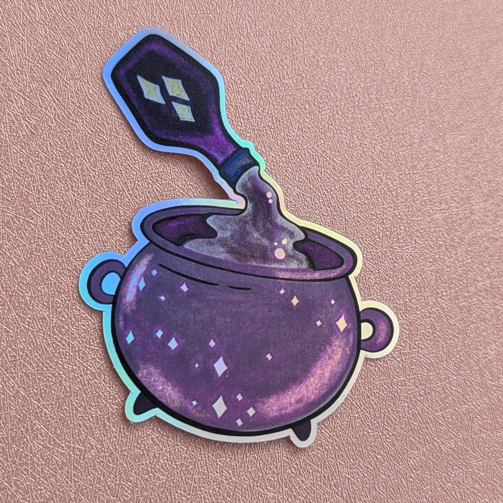 Sticker of a purple cauldron with a spoon on a pink background