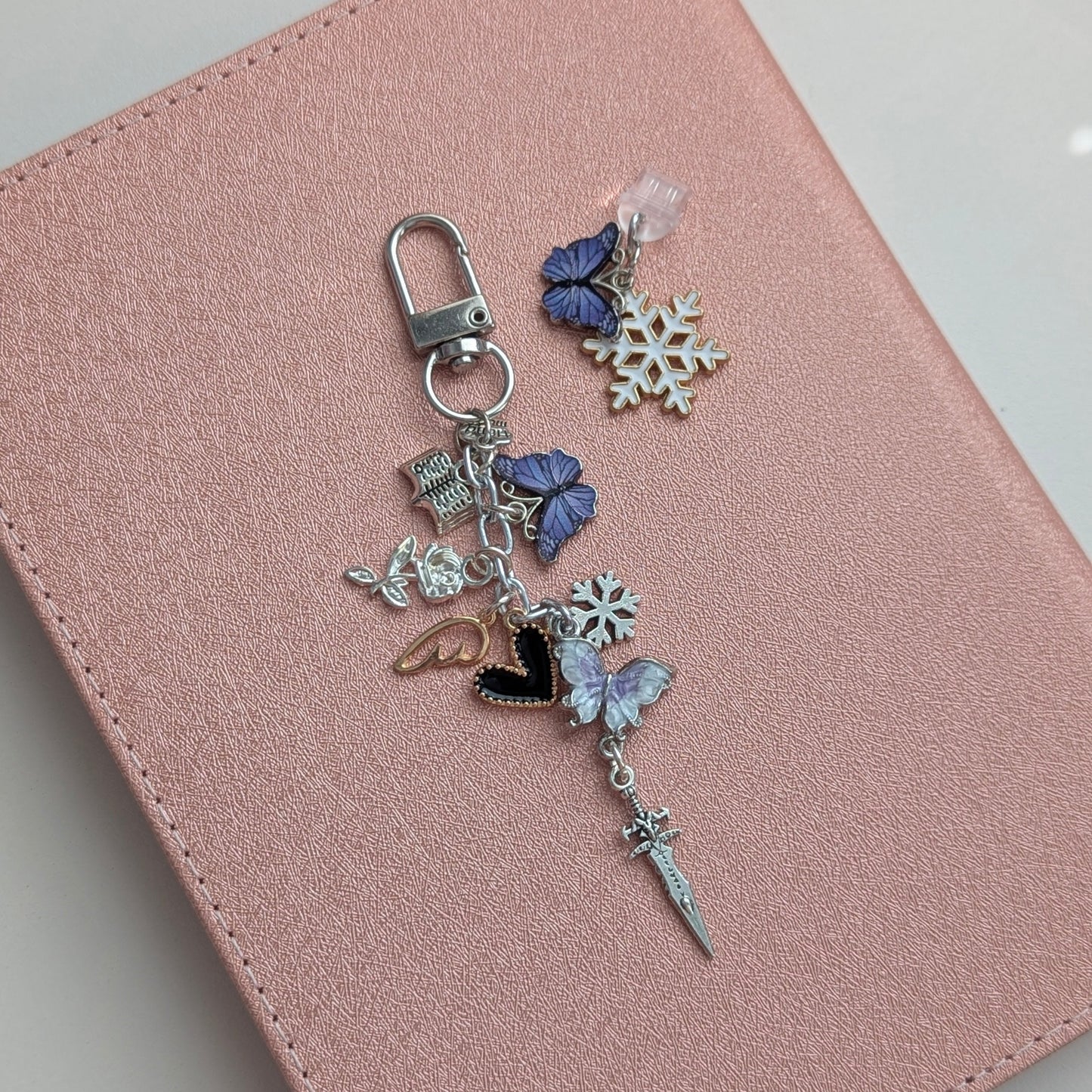Pink notebook with a decorative charm on a light gray background