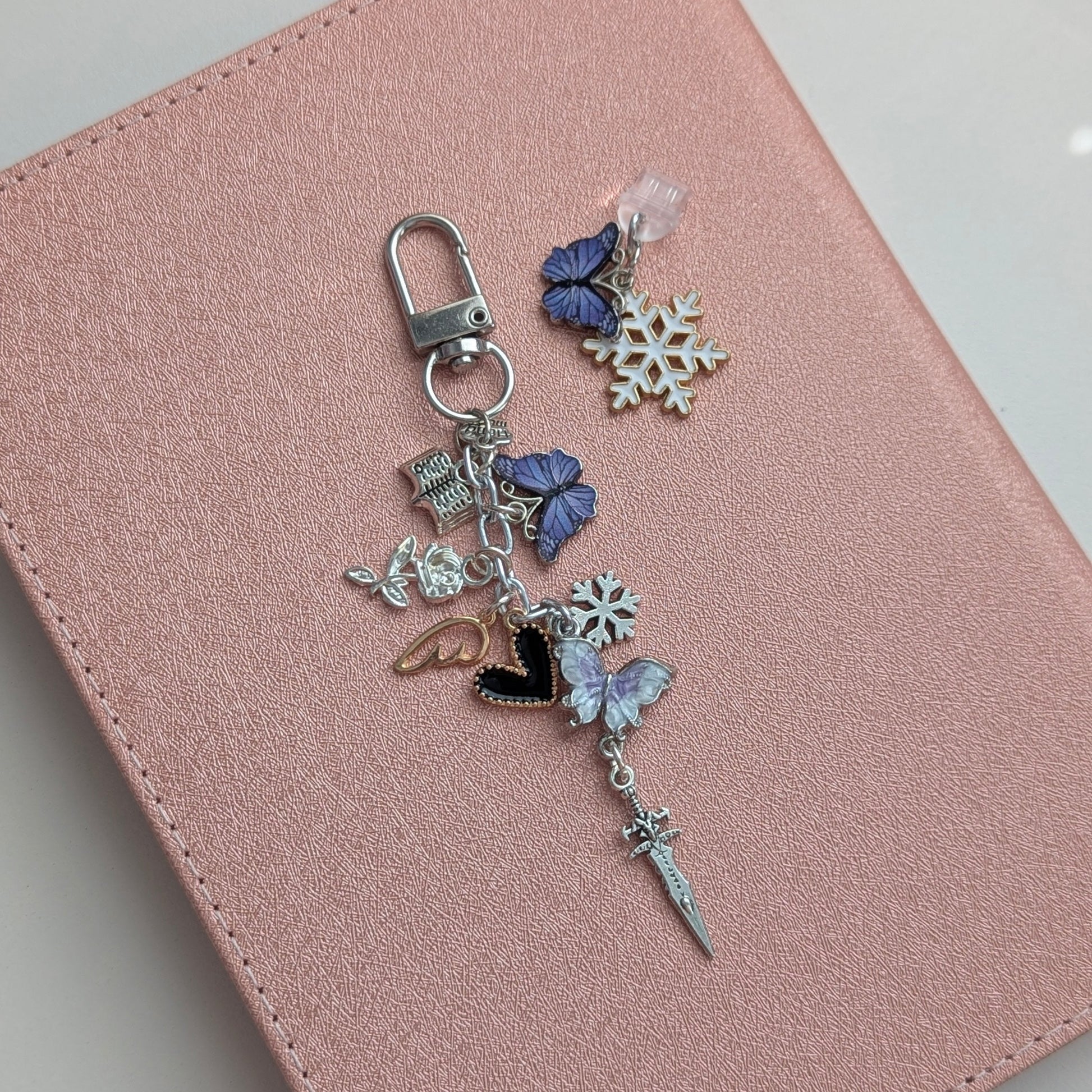 Pink notebook with a decorative charm on a light gray background