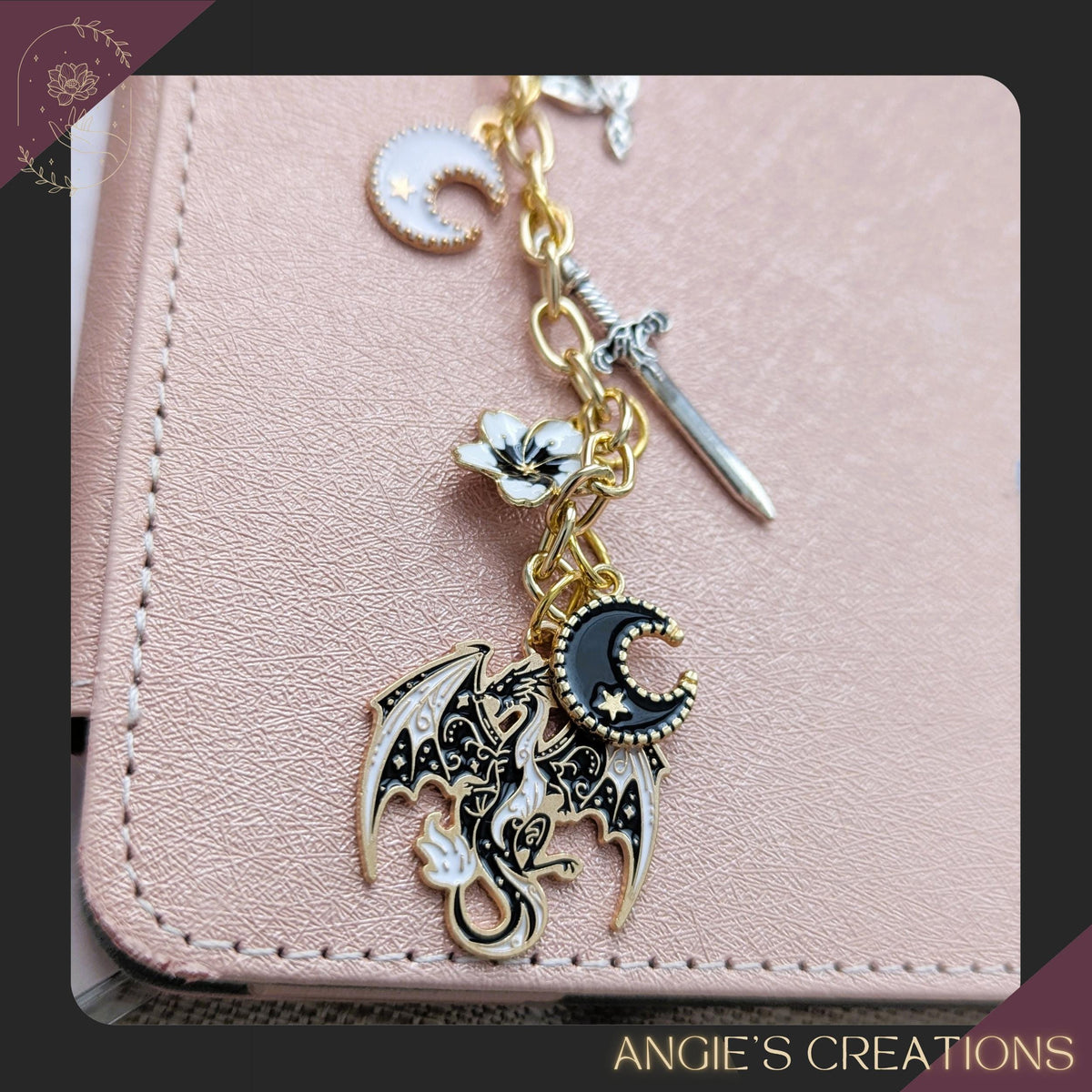 A silver chain Kindle charm displayed on a pastel planner, featuring dragon, moon, sword, star, and rose charms in a romantasy aesthetic.