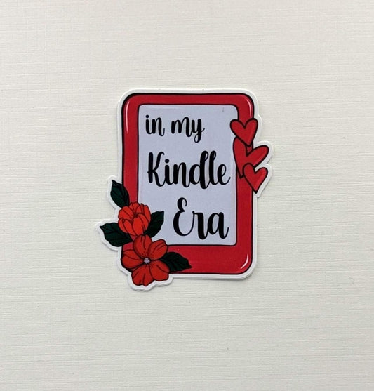 May include: A sticker featuring the phrase "in my Kindle Era" in black script, within a red border. The design includes red hearts and flowers with green leaves, set against a white backdrop.