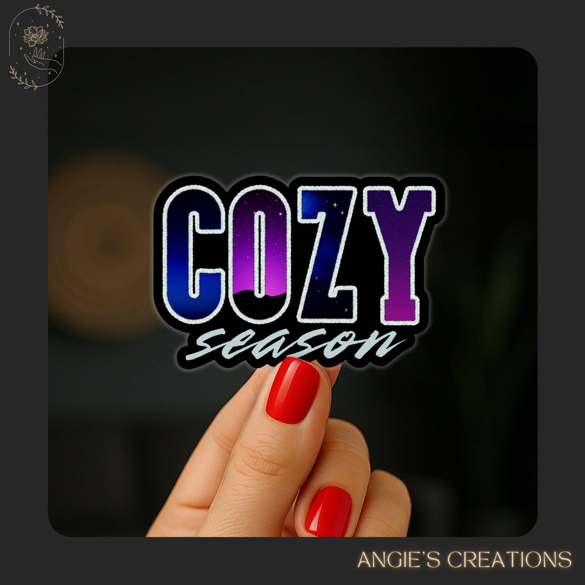 A hand holding a sticker with the word &quot;COZY&quot; in large letters, with the word &quot;Season&quot; written below it.