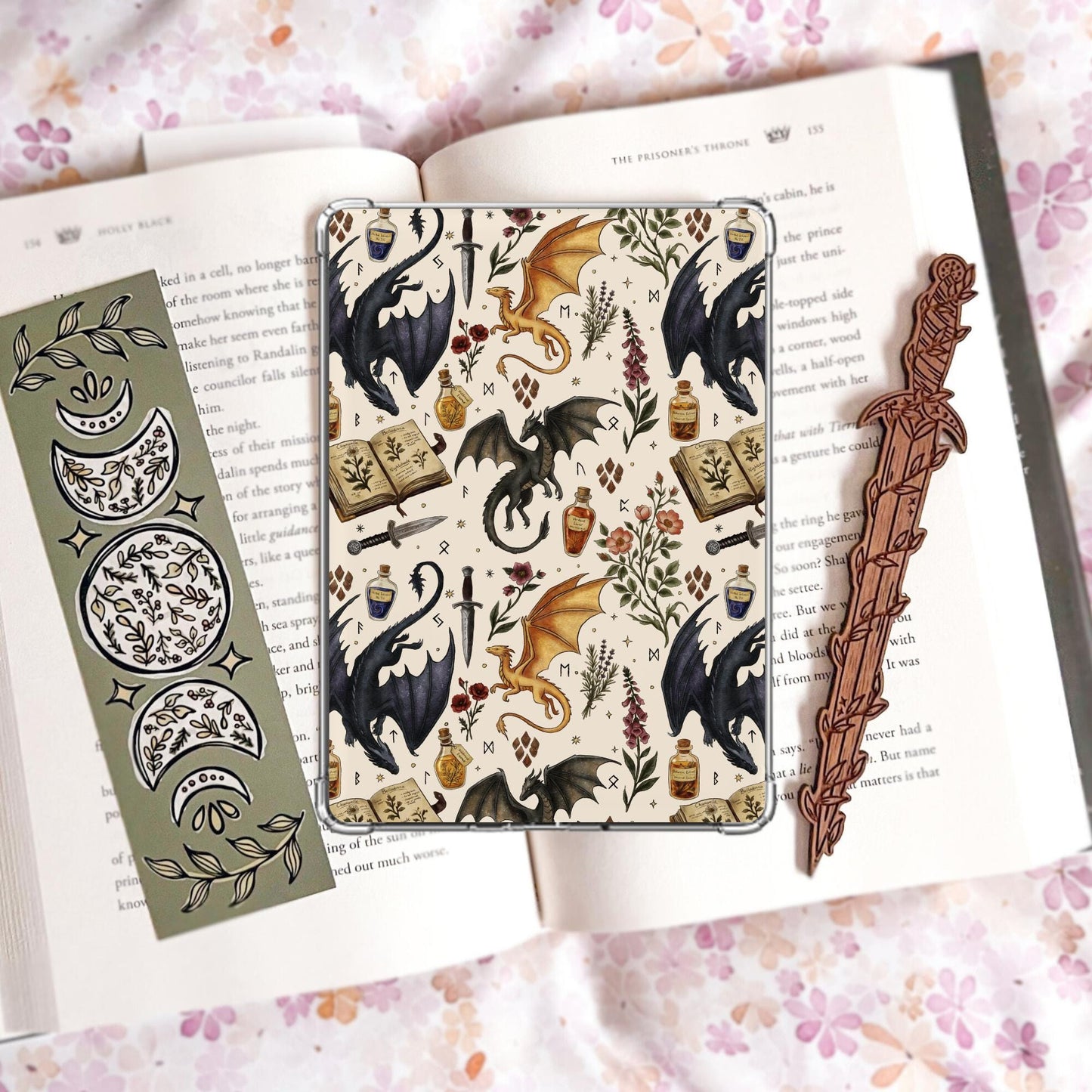 Handmade navy blue Kindle insert featuring hand drawn black and gold dragons, potion bottles, an open spell book and wildflowers in a repeating pattern, displayed on an kindle