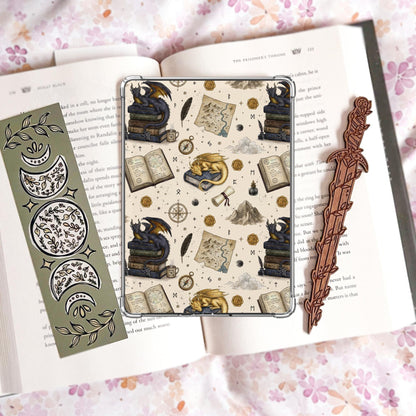 Cream Kindle insert pattern with a gold sleeping dragon and a dark dragon perched on stacked books, alongside a treasure map, compass, quill, ink well, and wax seals.