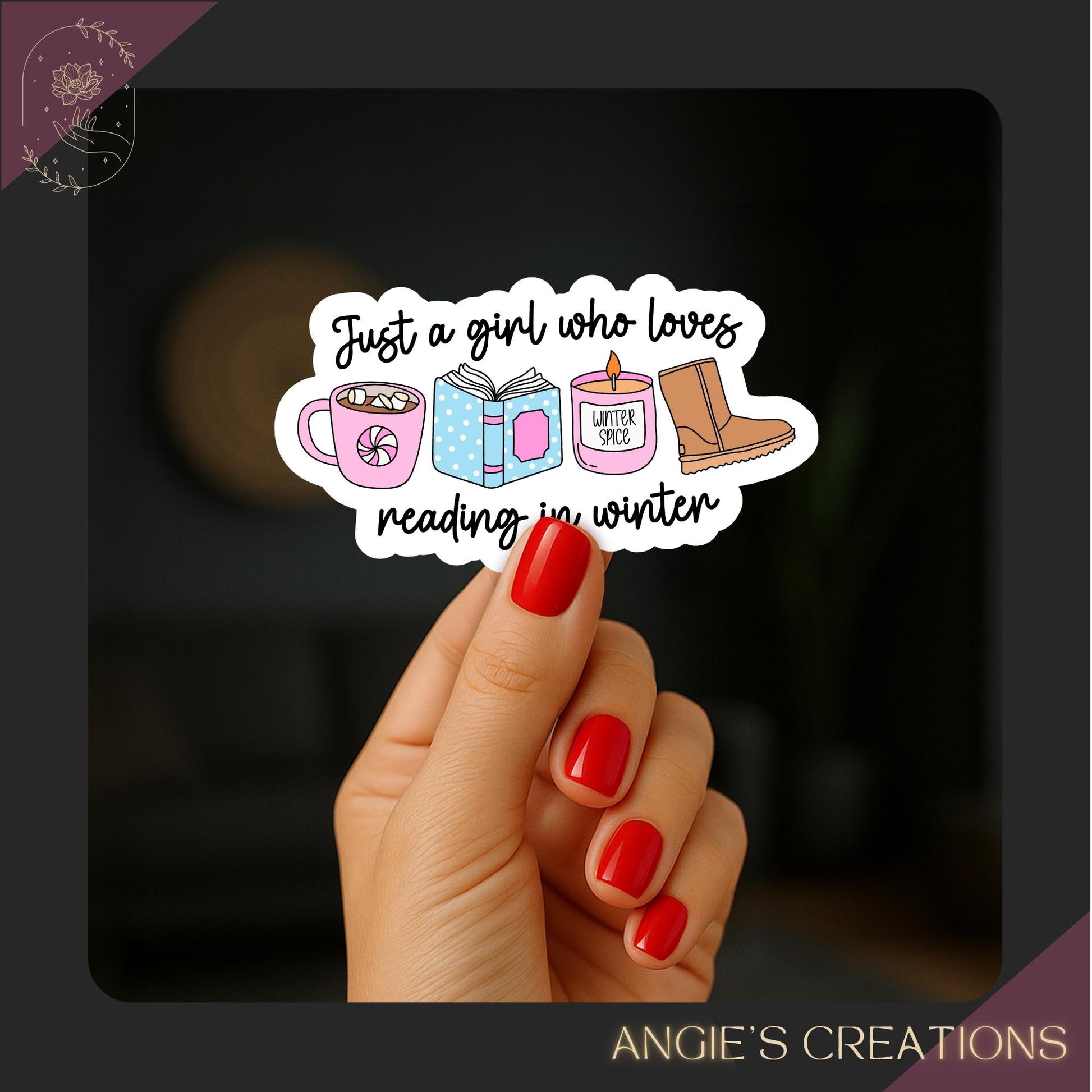 Hand holding a winter-themed bookish vinyl sticker against a softly blurred background. The sticker features illustrations of a pink mug of hot chocolate, an open book, a pink candle labeled ‘winter spice,’ and a pair of winter boots, with the phrase ‘Just a girl who loves reading in winter’ in handwritten script. Bright red nails create a cozy contrast. Handmade by Angie’s Creations, perfect for readers, winter lovers, and bookish decor.