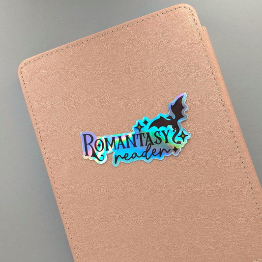 You didn't choose the romantasy life. It chose you. One chapter became one series became a TBR with its own postal code. This holographic sticker is for the girlie with a dragon on her Kindle, a book boyfriend in her heart, and zero apologies about either.