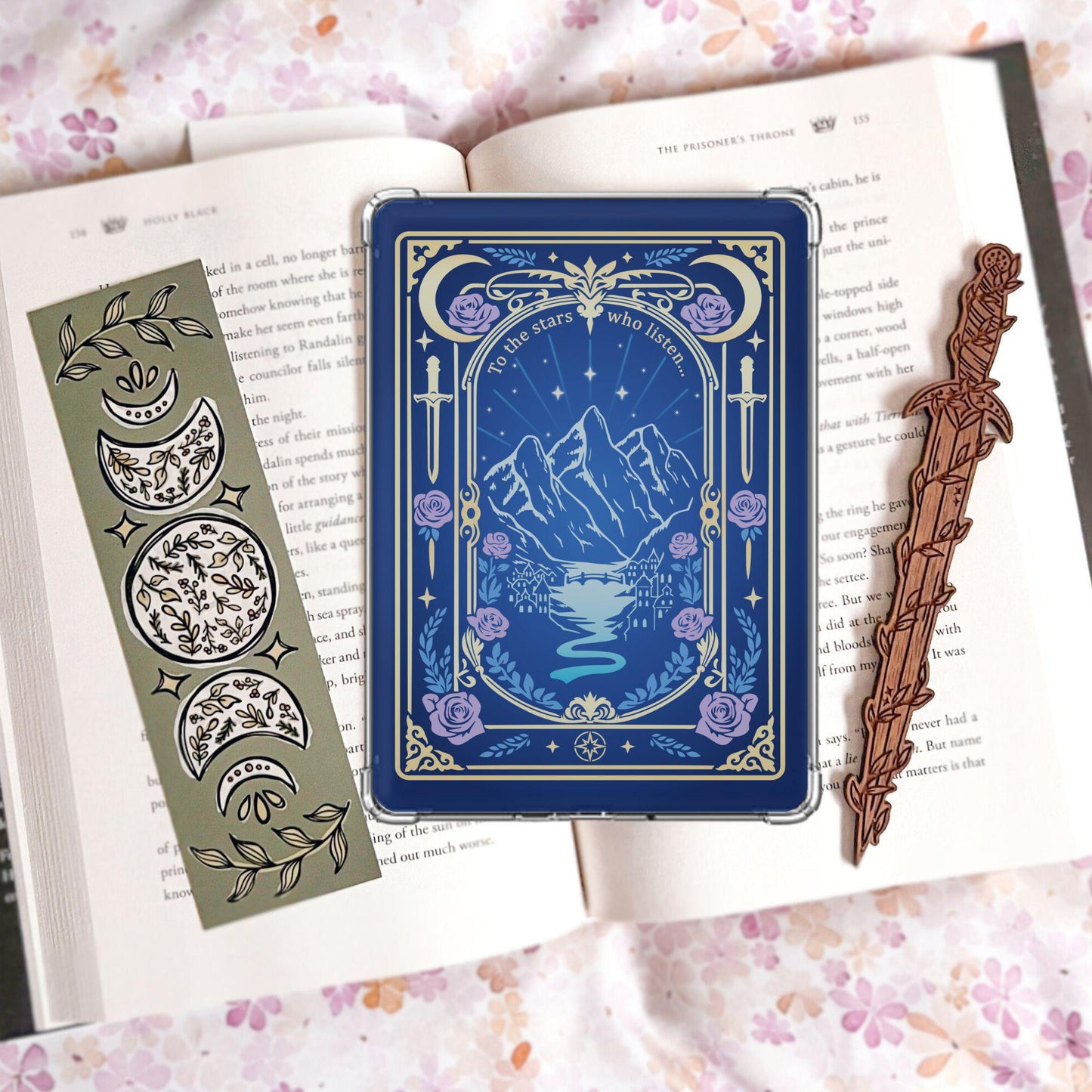 Handmade navy blue Kindle insert with gold tarot card border, mountain and castle landscape, purple roses, reading "To the stars who listen," displayed on an open book
