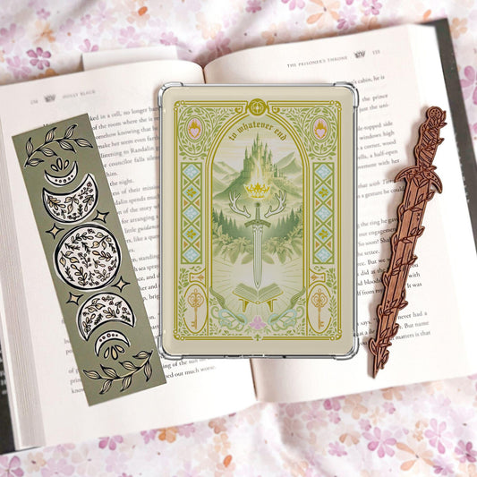 Handmade cream and green Kindle insert with ornate gold border, castle and mountain scene, sword crown and antlers, reading "To whatever end," displayed on an open book