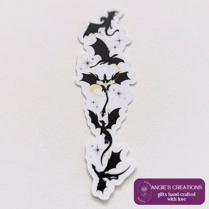 Black silhouette sticker featuring a vertical arrangement of dragons in flight, with small gold star accents, designed for Kindle or journal placement.
