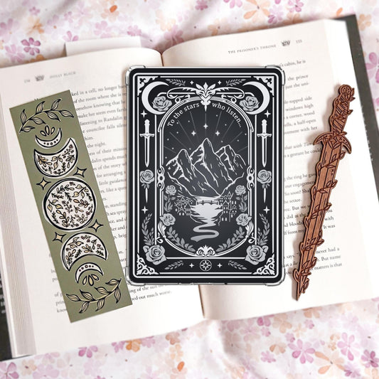 Black and silver tarot-card-style Kindle insert with mountains, a river, daggers, roses, moons, and the text "To the stars who listen."