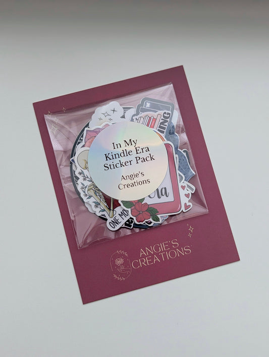 Angie's Creations "In My Kindle Era" holographic bookish sticker pack displayed in a clear resealable bag on a dark rose branded backing card, showing a collection of mixed die-cut stickers including romantasy, dragon, and reader-themed designs with the Angie's Creations logo. Handmade bookish sticker bundle designed in Ottawa Canada, perfect for Kindle cases, laptops, water bottles, journals, and planners.